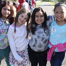 Four female students hugging and smiling.